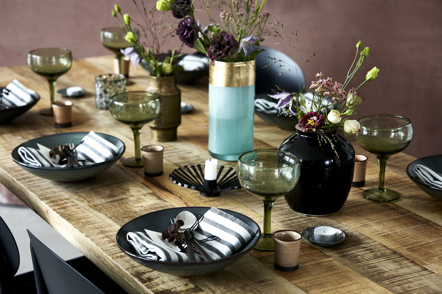 Gedeckter Tisch mit schön arrangierte Accessoires, wie Teller, Besteck, Vasen und Kerzen von House Doctor.
